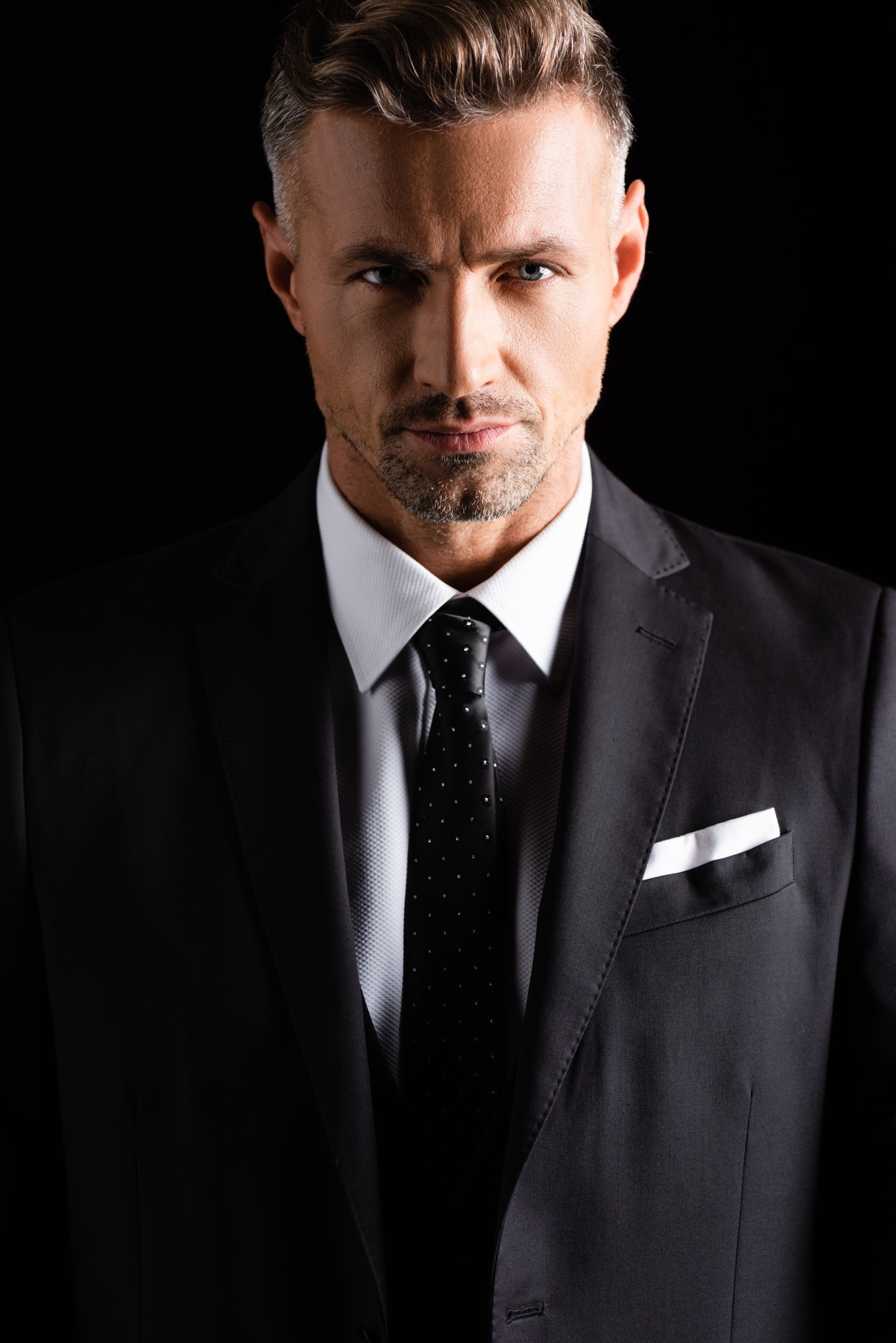 handsome businessman looking at camera isolated on black.jpg